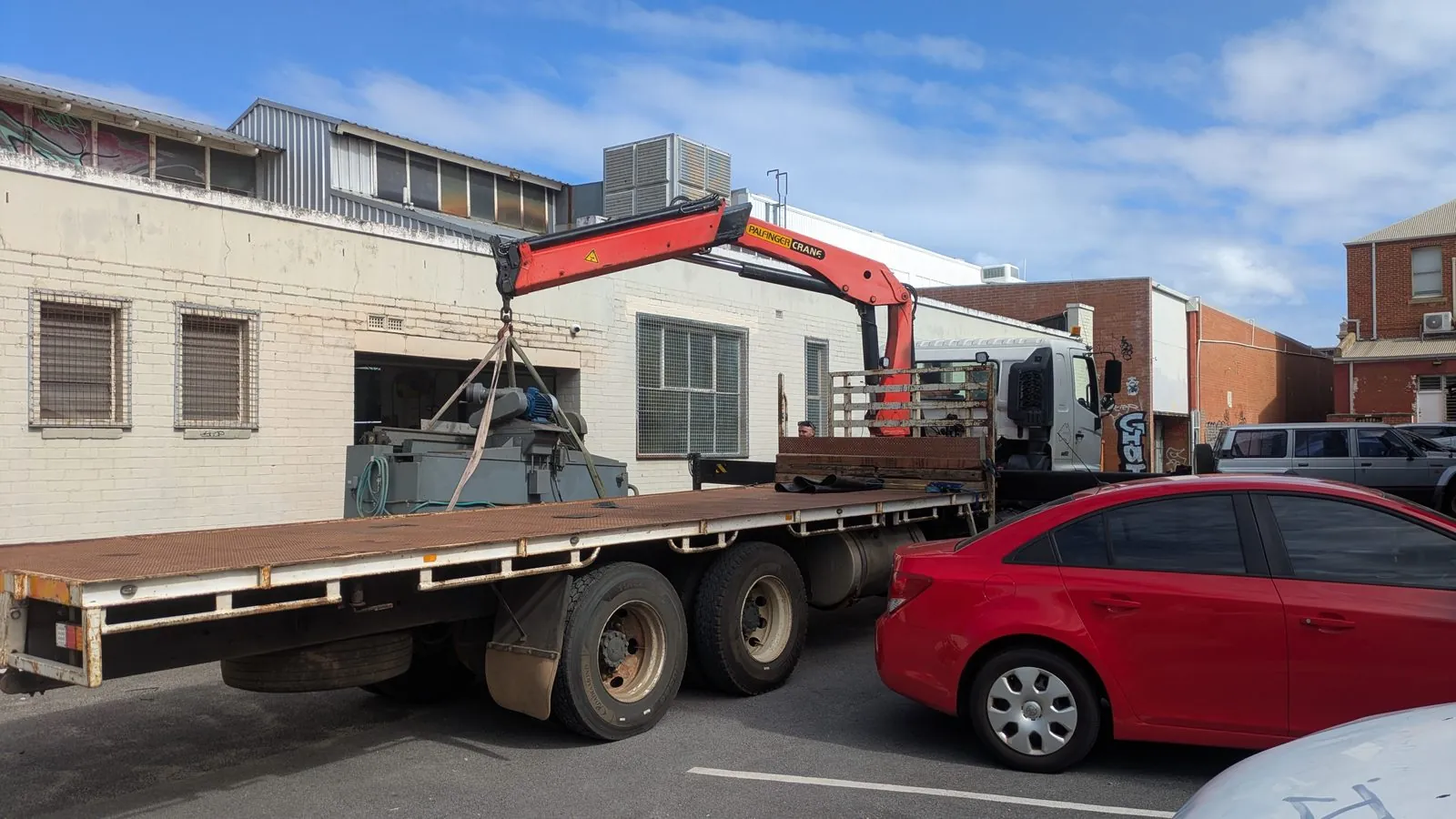Crane truck mid-lift on a commercial job site in Perth
