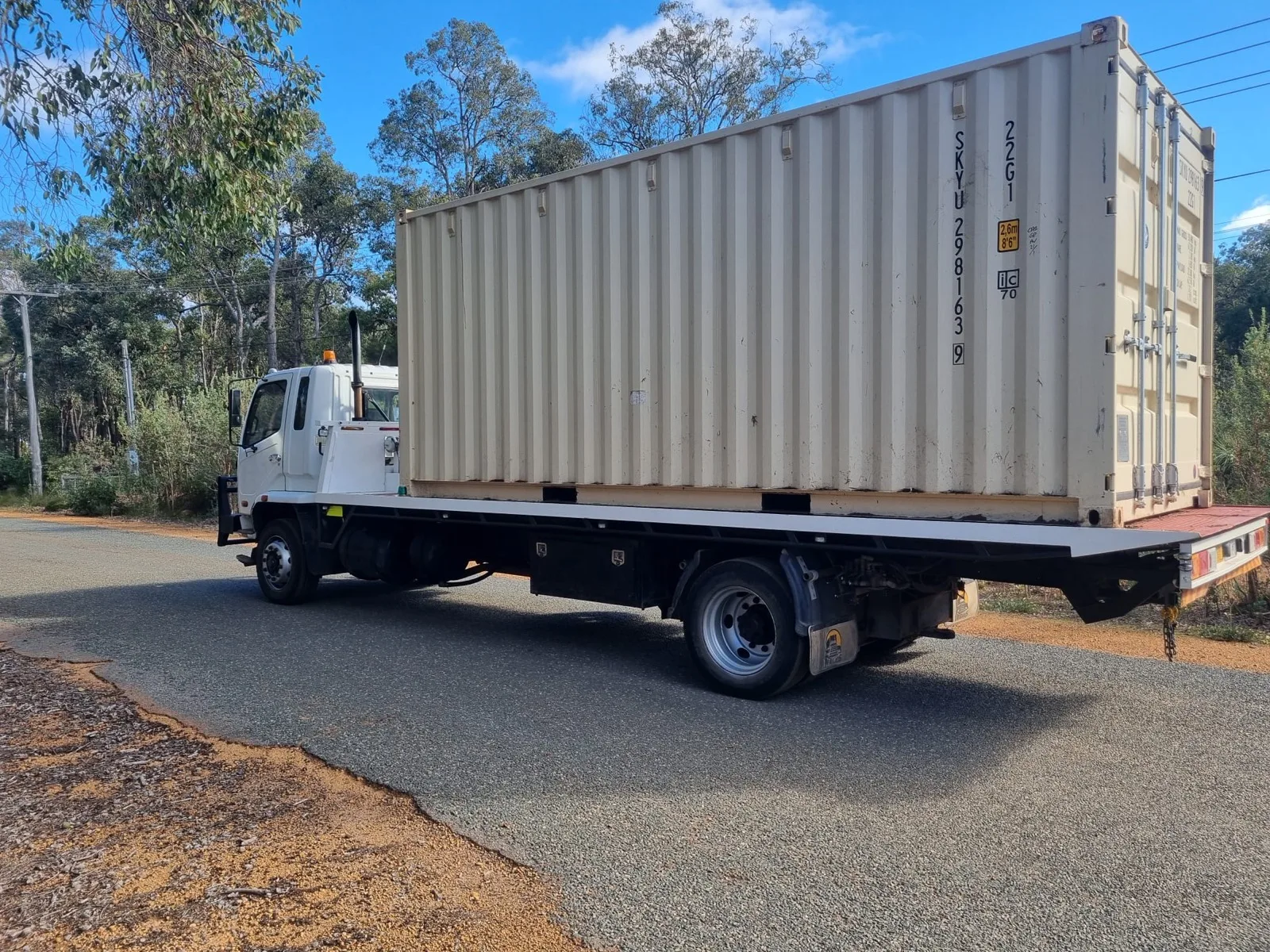 Australian Premium Logistics tilt tray loaded with a shipping container, strapped down and ready to move